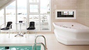 A modern bathroom with a large bathtub, two black chairs, and a small table. - 5 Star Holiday Home in Jelsa (Suldal)