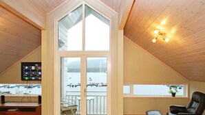 A spacious room with a high ceiling, wooden floors, a large window with a view of boats, a desk with a computer, and a comfortable seating area. - 5 Star Holiday Home in Jelsa (Suldal)
