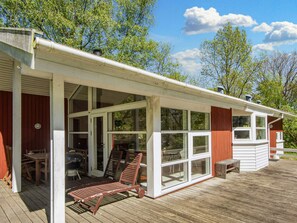 Un espacio al aire libre techado con terraza de madera, una parrilla y asientos.