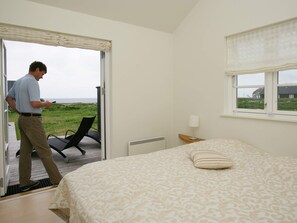 A bedroom with a bed, a chair, a window, and a view of the outdoors. - 5 Star Holiday Home in Nysted (Nysted)