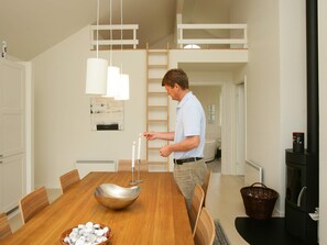 Una cocina moderna con una mesa de comedor, sillas, una lámpara colgante y una estufa negra.