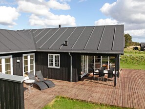 A modern house with a large deck, a covered outdoor seating area, and a sloped roof. - 5 Star Holiday Home in Nysted (Nysted)