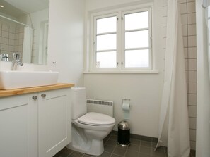 A bathroom with a white sink, a toilet, a window, and a shower curtain.
