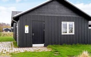 A black building with a door marked '7', a window, and a paved entrance.
