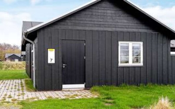 A black building with a door marked '7', a window, and a paved entrance.