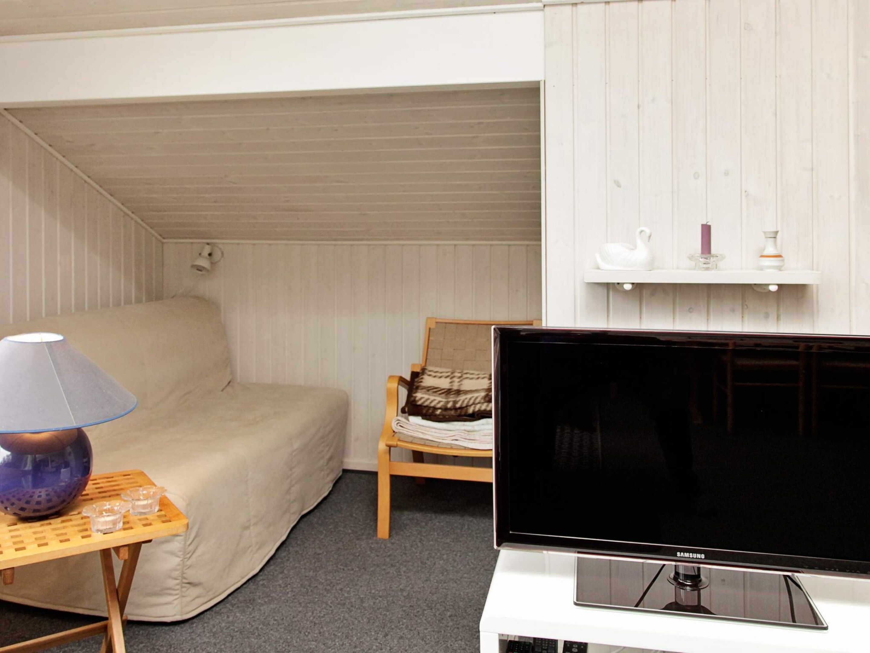 A room with a bed, a television, a lamp, and a small table with cups.