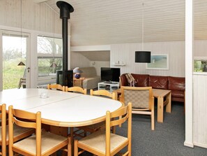 Ett rum med ett runt träbord, stolar, en soffa, en tv och en öppen spis.