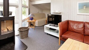 Ein gemütliches Wohnzimmer mit Kamin, einer Couch, einem Fernseher und einem Gemälde an der Wand.