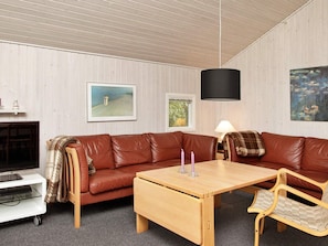 A cozy living room with a brown leather sofa, a wooden coffee table, and a wicker chair.