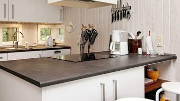 A modern kitchen with a central island, white cabinetry, and a hanging knife rack.