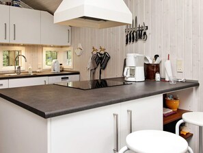 Een moderne keuken met een centraal eiland, witte kastjes en een hangende messenhouder.