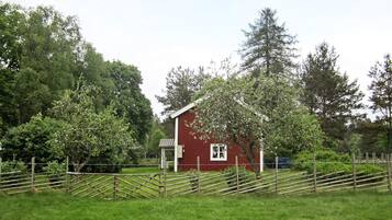 A red barn with a white door, surrounded by a wooden fence and lush green grass.