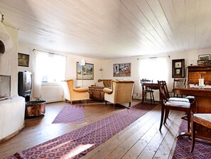 A living room with wooden flooring, a fireplace, a television, and a dining area with chairs and a table. - 5 Person Holiday Home in Jonkoping (Jonkoping)