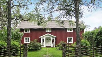 A red building with a white porch and a small garden in front.