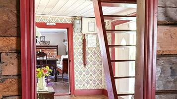 A wooden interior with a red-framed doorway leading to a dining area with a table and chairs.