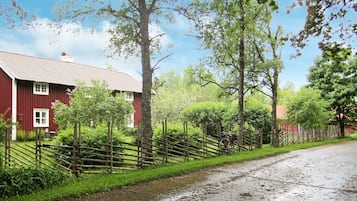 A rural road with a red barn and wooden fences.