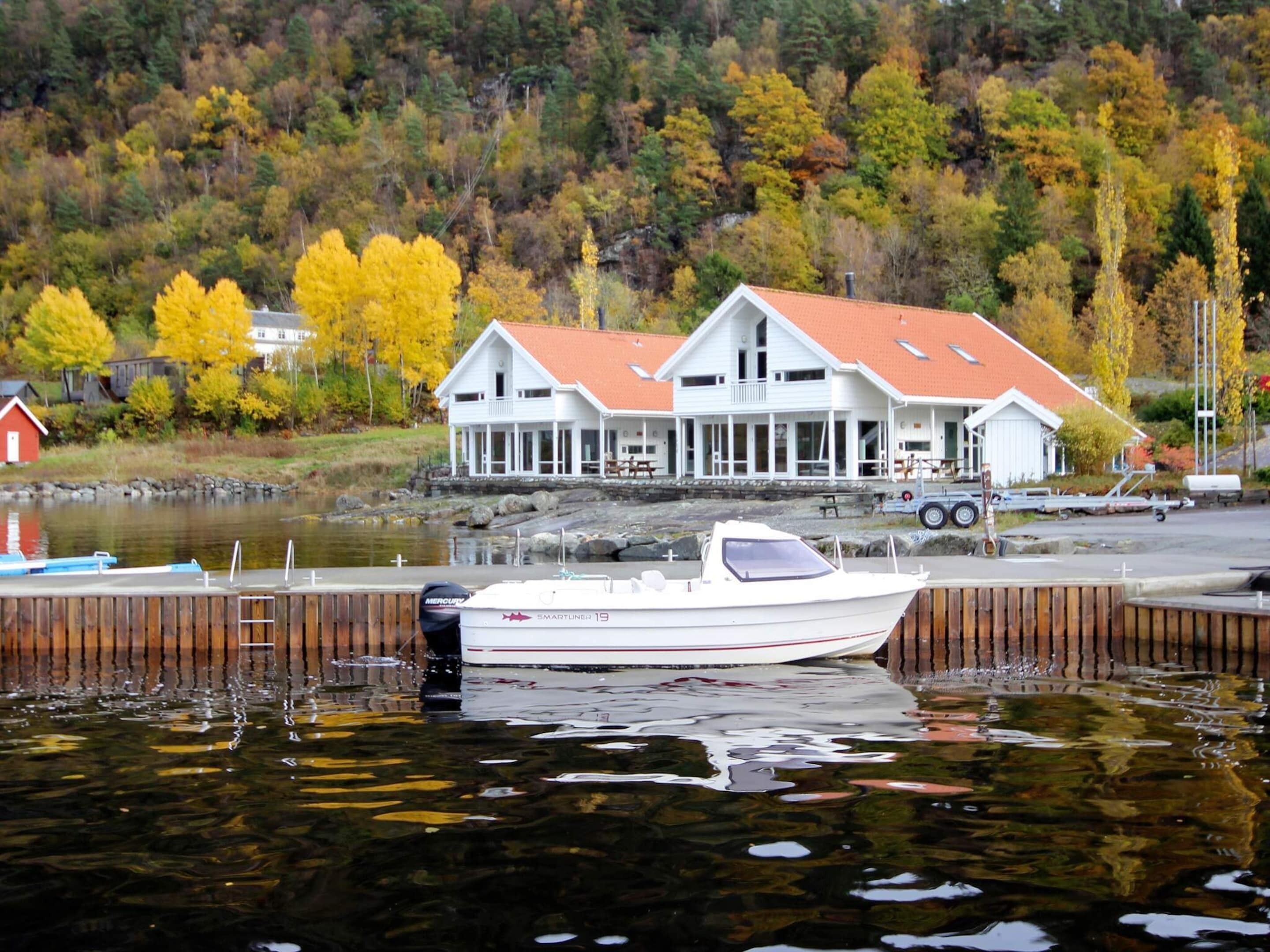 A white boat docked at a pier with a house in the background.