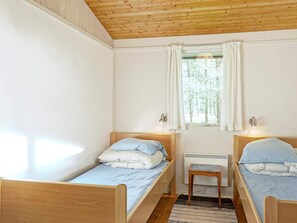 A small, cozy room with two wooden beds, a window with curtains, and a small table. - Cozy Holiday Home in Aakirkeby Bornholm near Sea (Akirkeby)