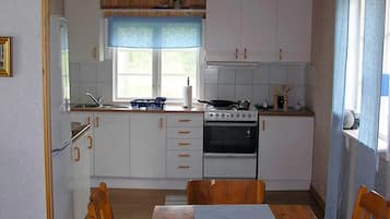 A compact kitchen with white cabinets, a stove, and a dining table with chairs.