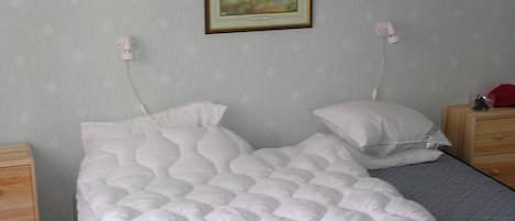A bedroom with a bed, two bedside tables, a nightstand, and a wall-mounted picture.