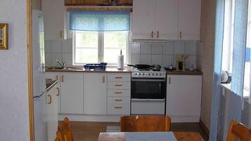 A compact kitchen with white cabinets, a stove, and a dining table with chairs.