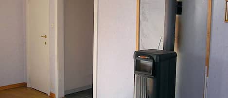 A room with a wood-burning stove, a white door, and a tiled floor.