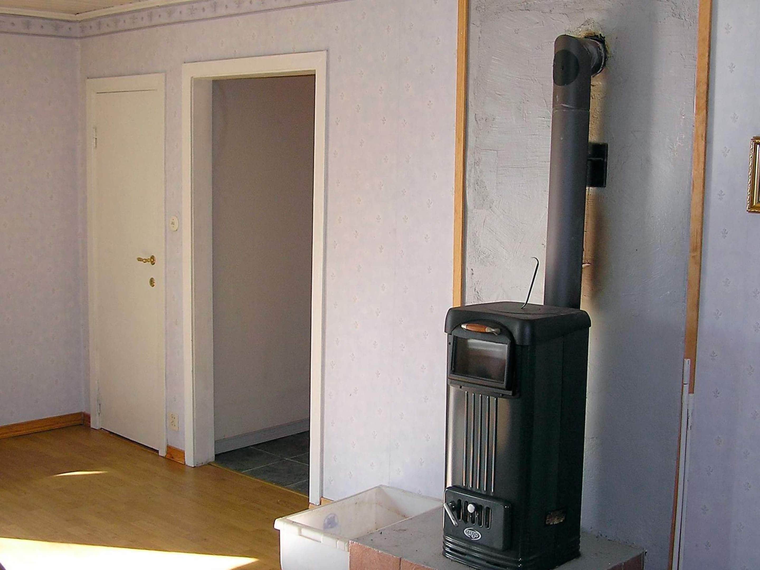 A room with a wood-burning stove, a white door, and a tiled floor.
