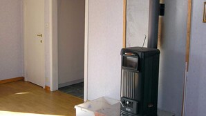 A room with a wood-burning stove, a white door, and a tiled floor. - 6 Person Holiday Home in Hacksvik (Håcksvik)