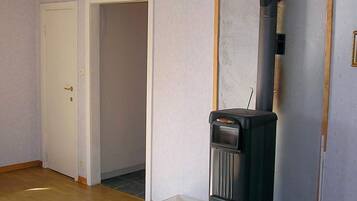 A room with a wood-burning stove, a white door, and a tiled floor.