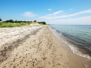 A beach with a boat on the shore, clear skies, and calm water. - 8 Person Holiday Home in Tranekaer (Tranekaer)
