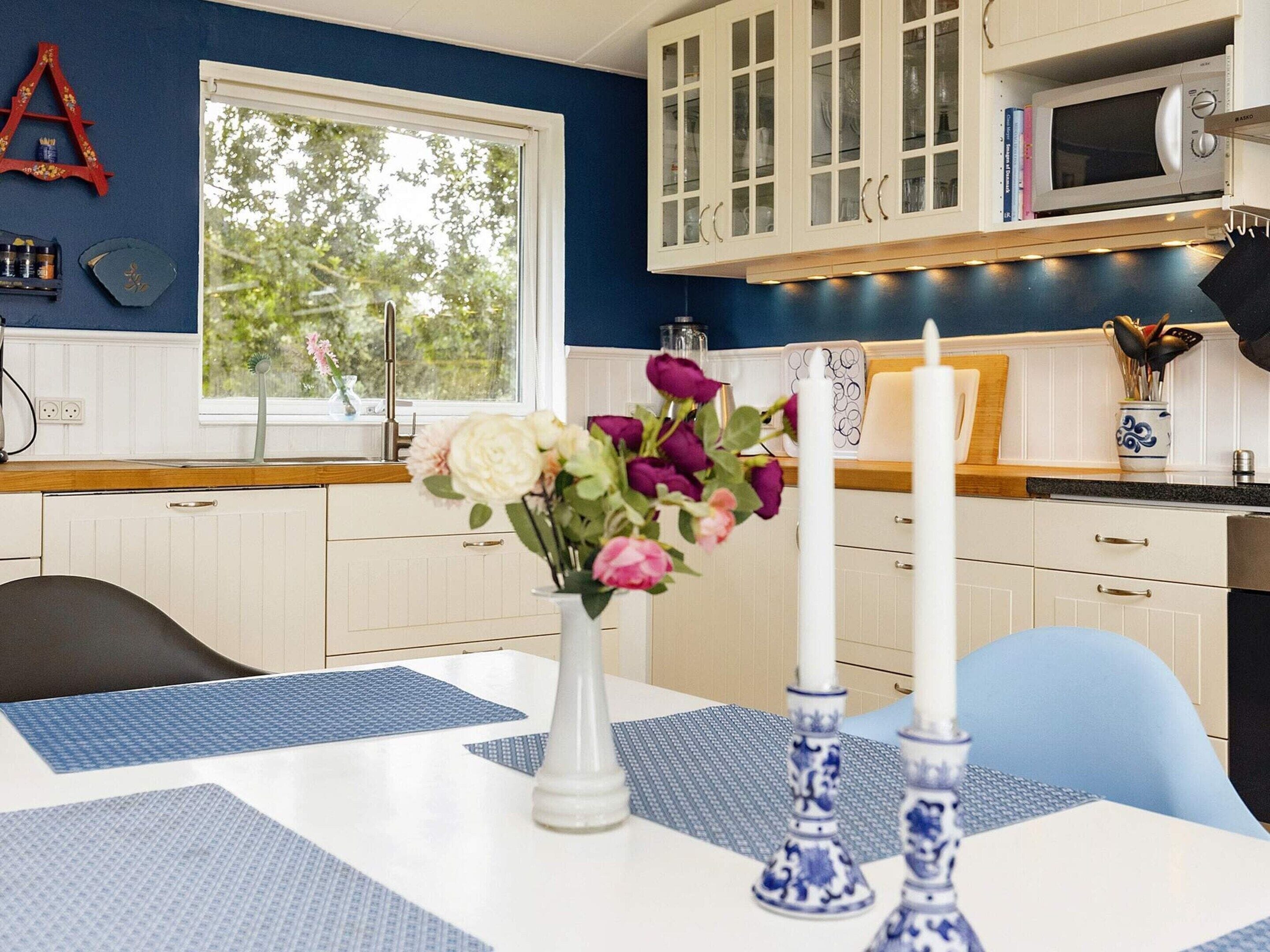 A kitchen with white cabinets, a microwave, and a window with a view of trees.