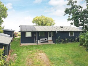 Een gelijkvloers huis met een voortuin, een bankje en een kleine tuin.