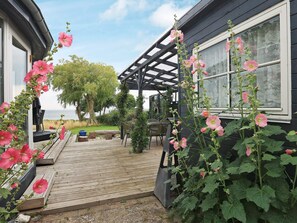A wooden deck with outdoor furniture, a pergola, and flowering plants. - 8 Person Holiday Home in Tranekaer (Tranekaer)