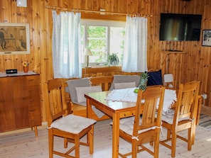 A wooden-paneled room with a dining table, chairs, a television, and a window with curtains. - 4 Person Holiday Home in Torsby (Torsby)