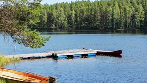 A calm lake with docked boats and a forest in the background. - 4 Person Holiday Home in Torsby (Torsby)