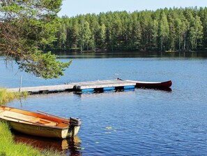 A calm lake with docked boats and a forest in the background. - 4 Person Holiday Home in Torsby (Torsby)