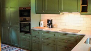 A kitchen with green cabinets, a built-in oven, a coffee maker, and a tiled backsplash. - 4 Person Holiday Home in Torsby (Torsby)