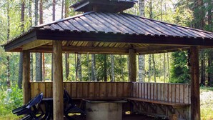 A wooden gazebo with a sloped roof, a bench, and a concrete table. - 4 Person Holiday Home in Torsby (Torsby)