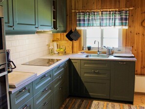 A kitchen with a built-in stove, a sink, and a window with plaid curtains. - 4 Person Holiday Home in Torsby (Torsby)