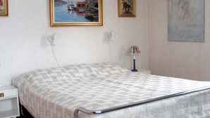 A bedroom with a bed, a nightstand, a lamp, and two framed pictures on the wall.
