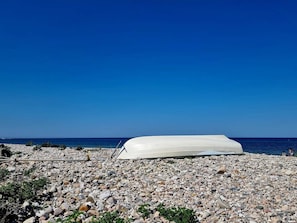 A white boat on a rocky beach with a clear blue sky. - 4 Star Holiday Home in Dronningmolle (Dronningmolle)