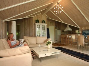 A cozy living room with a sofa, coffee table, and a dining area with chairs and a table. - 4 Star Holiday Home in Dronningmolle (Dronningmolle)