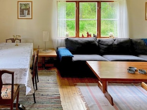 Un salon confortable avec un canapé, une table à manger et une fenêtre donnant sur un paysage verdoyant.