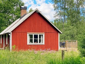 Ein rotes Holzgebäude mit Satteldach, einem Fenster und einer kleinen Veranda.