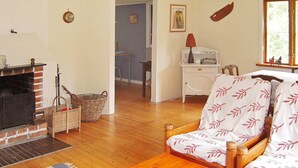 A cozy living room with a fireplace, wooden furniture, and a view of the outside through a window. - 6 Person Holiday Home in Osby (Osby)
