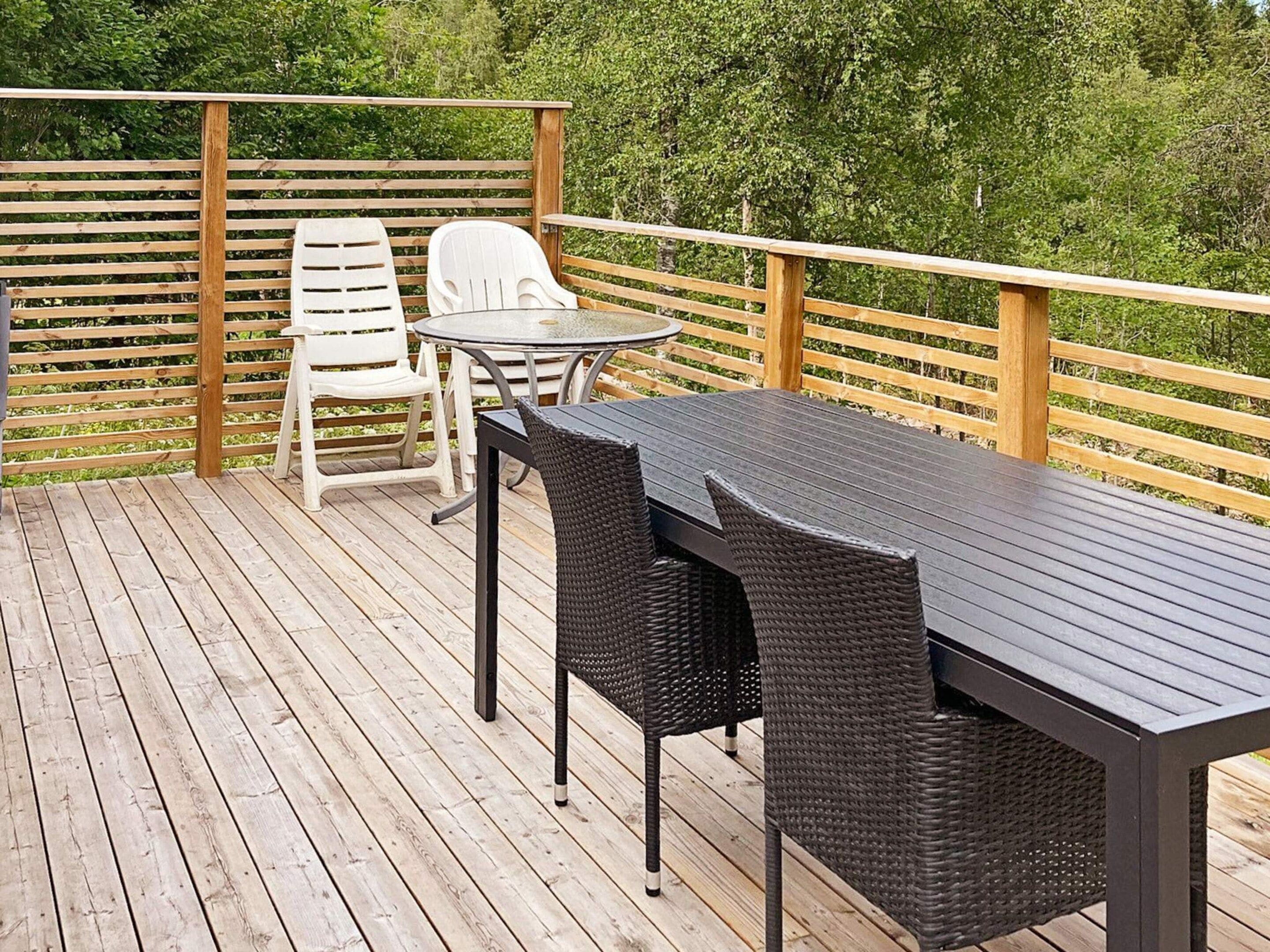 Una terraza de madera con una mesa y sillas, rodeada por una barandilla de madera.