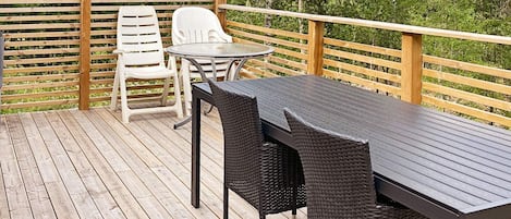 A wooden deck with a table and chairs, surrounded by a wooden railing.