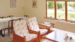 A cozy room with a dining table, two chairs, a sofa, and a window with a view of greenery. - 6 Person Holiday Home in Osby (Osby)