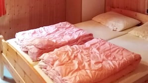 Una habitación pequeña y acogedora con dos camas de madera, cada una con un colchón y una almohada.