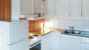 Una cocina con armarios blancos, estufa, pileta y piso de madera.